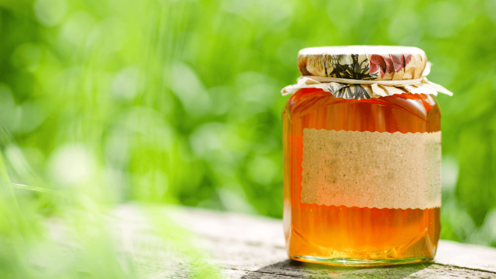 A jar of golden honey with a wooden honey dipper.