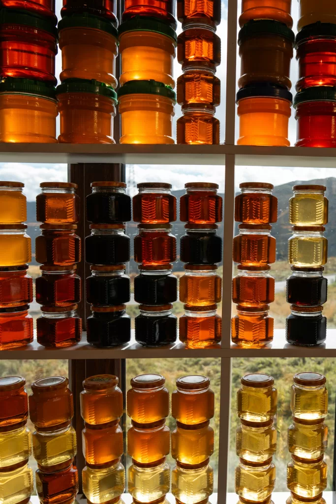 Different types of honey displayed in glass jars ranging from light to dark